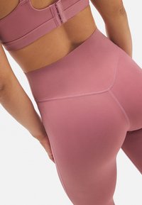 Conjunto de sujetador deportivo y leggings en un tono rosa rústico, que presenta una tela suave, diseño sin costuras, cintura alta y detalles de costura sutiles.