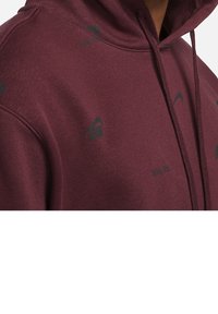 Maroon hoodie made of soft fabric, features a kangaroo pocket, drawstring hood, and subtle logo patterns in black.