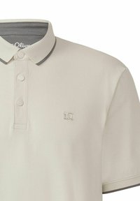 Beige Poloshirt aus strukturiertem Stoff, mit grauem Kragen und Knopfleiste. Gesticktes Logo auf der linken Brustseite.