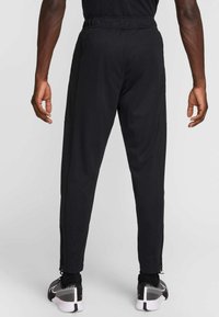 Μαύρο αθλητικό παντελόνι με ελαστική μέση, πλαϊνές τσέπες με φερμουάρ και στενές γραμμές στα πόδια, σχεδιασμένο για άνεση και ευκινησία.