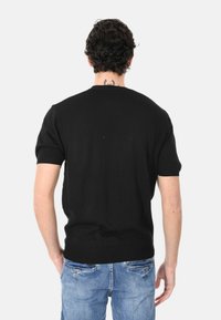 Maglione corto a maniche corte nero con scollatura rotonda e design aderente. Presenta una texture liscia e polsini a coste sulle maniche e sull'orlo.