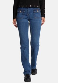 Jeans de mezclilla azul con un corte ajustado, que cuentan con dos bolsillos con acentos metálicos y un cierre de botón. La tela tiene una textura suave.
