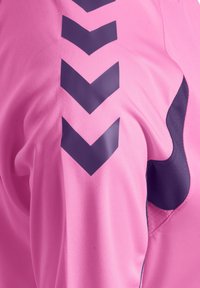 Close-up of pink fabric with black chevron stripes and a black curved design on the side, showing texture and stitching details.