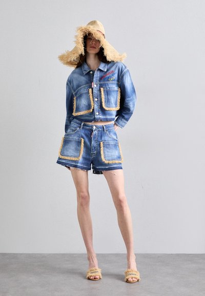 Denim takki ja shortsit, joissa on repaleiset reunat, brodeeratut yksityiskohdat ja suuret taskut. Kudottu olkihattu, jossa on tupsu yksityiskohtia.