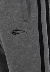 Graue Sweatpants aus einem weichen Baumwollmix, mit schwarzen seitlichen Streifen und einer dezenten schwarzen Logo-Stickerei auf der Vorderseite.