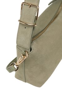 Grüne Wildleder-Schultertasche mit goldenen Beschlägen, ausgestattet mit einem breiten, verstellbaren Tragegurt und einem Reißverschlussverschluss entlang der oberen Kante.