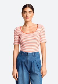 Striped short-sleeve top with a scoop neckline in white and orange, paired with high-waisted denim trousers featuring pleats and a button closure.