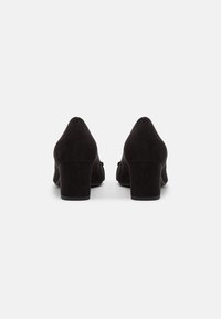 Czarne zamszowe buty na słupku z wydłużonym czubkiem i gładką teksturą. Minimalistyczny design z zaokrągloną piętą i bez widocznych ozdób.