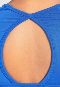 Primo piano di un top senza maniche blu con un'apertura arrotondata sulla parte superiore della schiena, che rivela la pelle nuda.