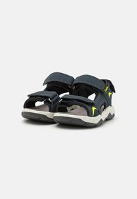 Sandali blu con accenti neri, cinturini in Velcro e suola in gomma strutturata. Presentano una soletta imbottita e un dettaglio del logo verde contrastante.