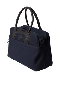 Marine canvas tas met zwarte leren handvatten, rechthoekige vorm, ritssluiting en voorvak. Geconfigureerde stof en subtiele logodetail.