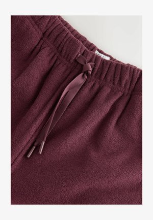 Burgunderfarbene Fleecehosen mit einem elastischen Bund und einer Kordel zum Festziehen. Weicher Stoff mit gerippten Details am Bund.
