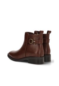 Botas de cuero marrón hasta el tobillo con punta redonda, tacón bajo apilado, detalle de hebilla lateral y textura suave.
