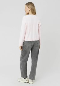 Pull court rose clair à manches longues, texture douce et ourlet côtelé, associé à un jean gris taille haute et des baskets blanches.