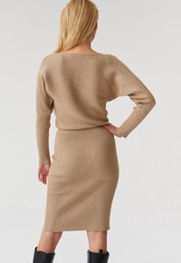 Beige ribbad tröja och kjolset, med långa ärmar, båturringning och en figurnära midikjol med elastisk midja.