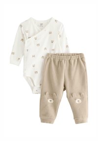 Lichtgewicht katoenen babyset met een crème gekleurde romper met lange mouwen en berenprint, en beige geribbelde broek met zakken in de vorm van berengezichten.