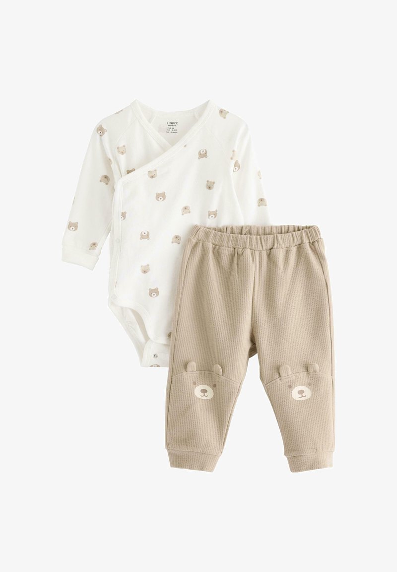 Lichtgewicht katoenen babyset met een crème gekleurde romper met lange mouwen en berenprint, en beige geribbelde broek met zakken in de vorm van berengezichten.