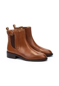 Botas de cuero marrón hasta el tobillo con un acabado suave, paneles laterales elásticos y un detalle de hebilla de metal en la parte trasera. Tacón block resistente.