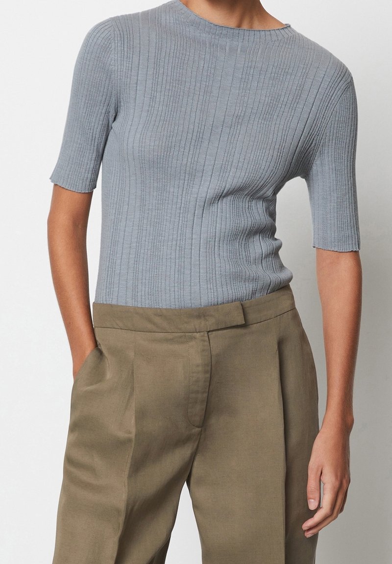 Haut gris à manches courtes et côtelé avec un col rond, assorti à un pantalon taille haute olive avec des plis et des poches latérales.