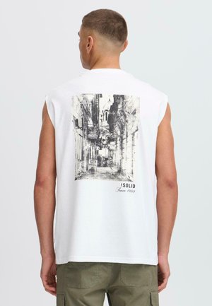 Camisa sin mangas blanca con una impresión de una escena callejera en blanco y negro en la parte posterior, con el texto "!SOLID Desde 1999" en la esquina inferior.