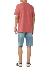 Rode heidegrijze t-shirt met korte mouwen in combinatie met lichtblauwe denim shorts. De outfit wordt compleet gemaakt met witte sneakers met zwarte accenten.
