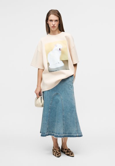 Υπερμεγέθη ανοιχτό μπεζ φούτερ με σχέδιο γάτας, συνδυασμένο με τζιν φούστα με καμπυλωτές ραφές. Συμπληρωμένο με μπεζ τσάντα και παπούτσια με λεοπάρ σχέδιο.