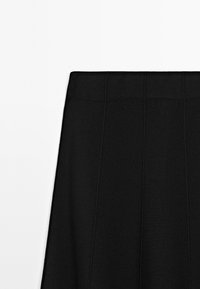 Schwarzer Rock mit strukturiertem, geripptem Muster und vertikalen Nähten. Der Stoff wirkt glatt mit einem strukturierten Bund, der oben beschnitten ist.