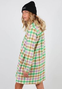Robe chemise en flanelle à carreaux verts, marron et violets. Manches longues avec poignets boutonnés, tissu léger avec une coupe décontractée.