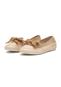 Beige balletschoenen gemaakt van gladde en textuurmaterialen, met een centraal strikdetail en contrasterende stiksels langs de randen.