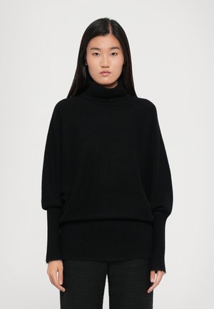 Jersey de cuello alto negro con un corte holgado, puños y dobladillo acanalados, hecho de un material de punto suave, con una textura lisa y elegante.