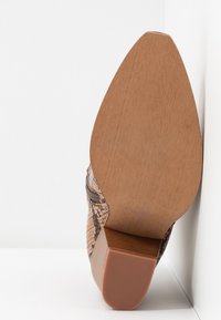 Brown snakeskin ankle boot with a zipper, featuring a pointed toe and a textured wooden heel with ribbing for grip.