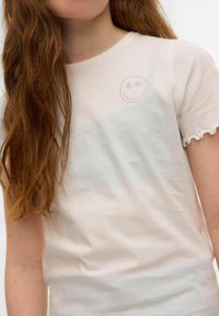 Ljusrosa bomullströja med rund halsringning och korta, vågiga ärmar. Har en pärlprydd smiley face-design på bröstet.