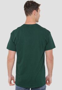 Green cotton t-shirt with short sleeves, a round neckline, and a relaxed fit, featuring a smooth texture and simple design.