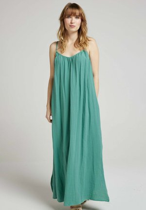 Robe maxi en teal, en tissu léger. Elle présente des bretelles fines, un buste froncé et arrive jusqu'au sol avec une silhouette fluide.