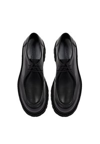 Zapatos de cuero negro con punta redondeada, diseño de cordones y suela de goma texturizada. Superficie lisa con un detalle mínimo.