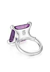 Anillo de plata con una gran gema triangular de color púrpura. La banda es lisa, mientras que el engaste presenta acentos curvados y decorativos.