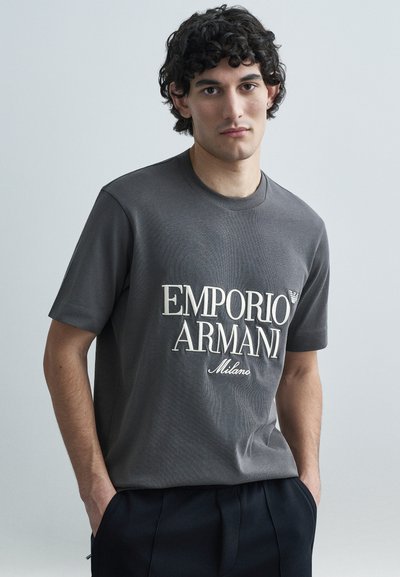 Grijs katoenen T-shirt met een groot wit logo met de tekst "EMPORIO ARMANI" en "Milano". Klassieke ronde hals en korte mouwen.