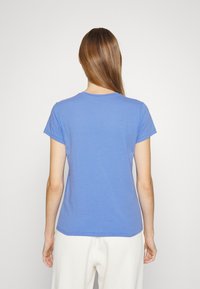 Krátký rukáv modrého trička s kulatým výstřihem a uvolněným střihem, vyrobeného z měkkého materiálu, s hladkou texturou a bez viditelných vzorů.