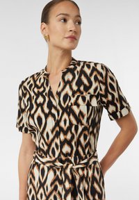 Sukienka z krótkim rękawem, zdobiona czarnym, brązowym i kremowym wzorem zwierzęcym, z kołnierzykiem w kształcie litery V, kieszonką z przodu i pasującym paskiem z materiału.
