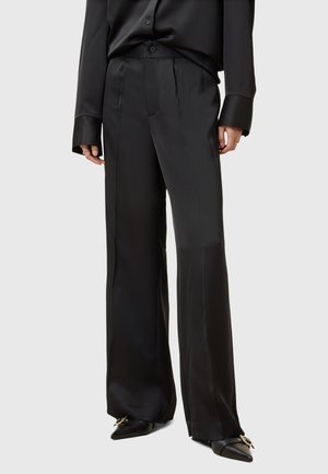 Zwarte satijnen wijde broek met plooien, een gladde afwerking en een op maat gemaakte pasvorm, gecombineerd metpuntige ballerina's.
