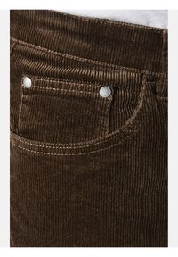 Brown corduroy pants with a ribbed texture, featuring a front pocket and silver button hardware. White stitching outlines the pocket.