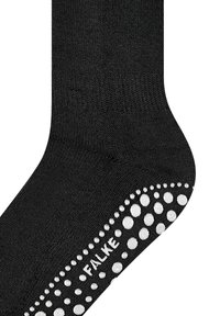 Musta sukka, joka on valmistettu pehmeästä materiaalista ja jossa on teksturoitu pohja valkoisilla liukumattomilla pisteillä. "FALKE"-logo on kohopainettu valkoisena sivuun.