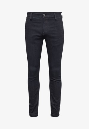 Jean slim noir avec fermeture devant par bouton et zip, passants de ceinture et design cinq poches, présenté sur fond blanc.