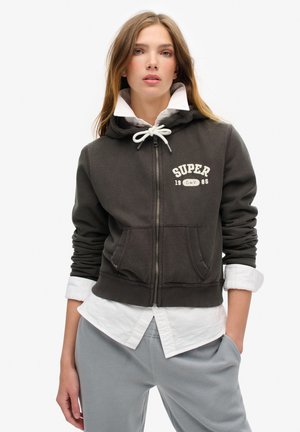 Gray zip-up hoodie made of soft fabric with a front pocket, contrasting white drawstrings, and "SUPER 1985" text on the chest.