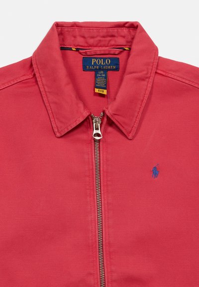 Rdeča jakna z zadrgo in ovratnikom, modra značka Polo Ralph Lauren na prsih ter etiketa znamke znotraj ovratnika, ki prikazuje velikost L/G (14-16).
