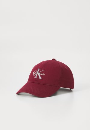 Bordeaux katoenen pet met een gebogen klep, met een zilver geborduurd "Calvin Klein" logo en een accentueerde letter "K" aan de voorkant.