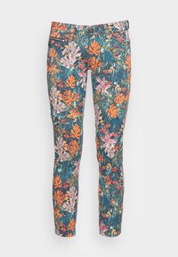 Tætsiddende bukser med et dristigt tropisk blomstermotiv i orange, pink og grønne nuancer, der har lynlås og knaplukning foran.