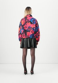 Quilted bomber jacket with a vibrant floral pattern in pink, blue, and black. Paired with a black leather skirt and black tights.