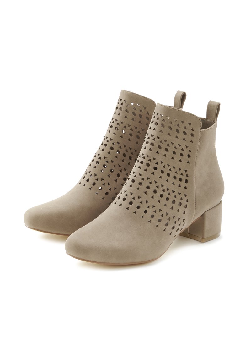 Botas de tobillo beige con patrones geométricos cortados, material de ante suave, punta afilada y un tacón bajo en bloque. Cuenta con lengüetas de agarre en la parte posterior.