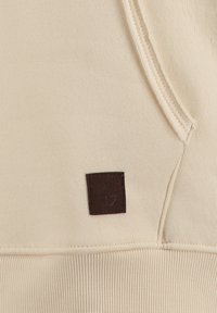 Crème-kleurige sweatshirt met een gestructureerd oppervlak, voorzien van een bruin lederen label met reliëfbranding en geribbelde boorden aan de onderkant.